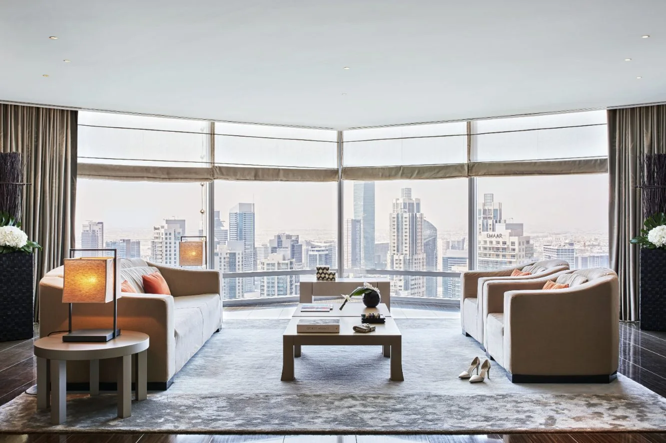 A suite living room at Armani Hotel Dubai with curved sofas, low tables and floor-to-ceiling windows onto the Downtown Dubai skyline